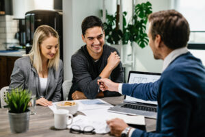 happy couple having meeting with real estate agent analyzing blueprints while communicating happy couple having meeting with real estate agent analyzing blueprints while communicating