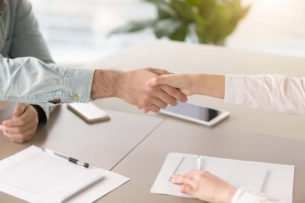 male hand shaking hand young female office desk scaled 1